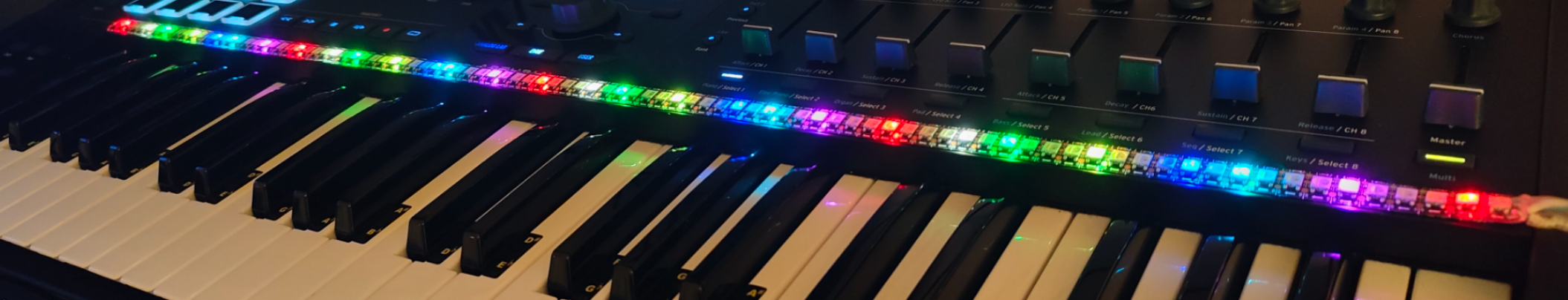 DreamScaler's RGBW LED strip glowing red, green, blue and purple along a keyboard, with colored light reflecting on the white and black keys.